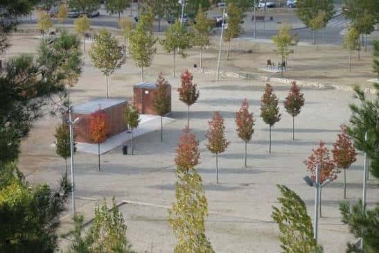 Vista aérea del parque con zonas verdes, árboles estacionales y mobiliario urbano