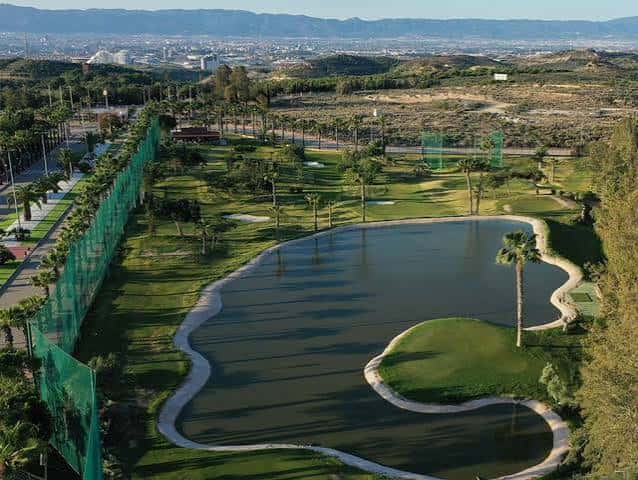 Vista aérea del campo de golf MontePríncipe con laguna y zonas de práctica