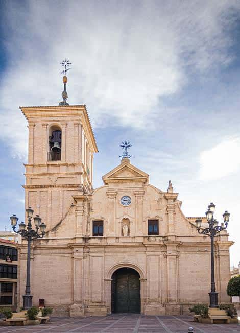 Fachada principal de la iglesia con detalles arquitectónicos barrocos y farolas ornamentales en la plaza