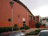 Vista exterior del Pabellón Deportivo Serrerías con fachada naranja y escaleras de acceso
