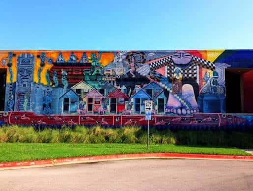 Vista frontal de la fachada de la biblioteca con un mural colorido y detallado