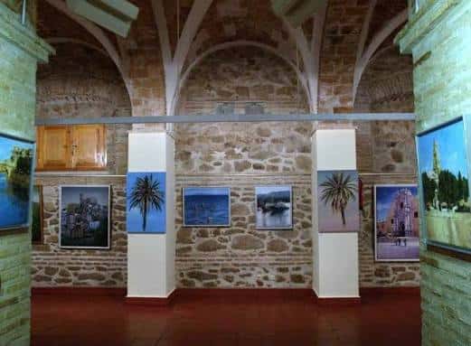 Vista general del interior de la sala de exposiciones con bóvedas de piedra y obras colgadas