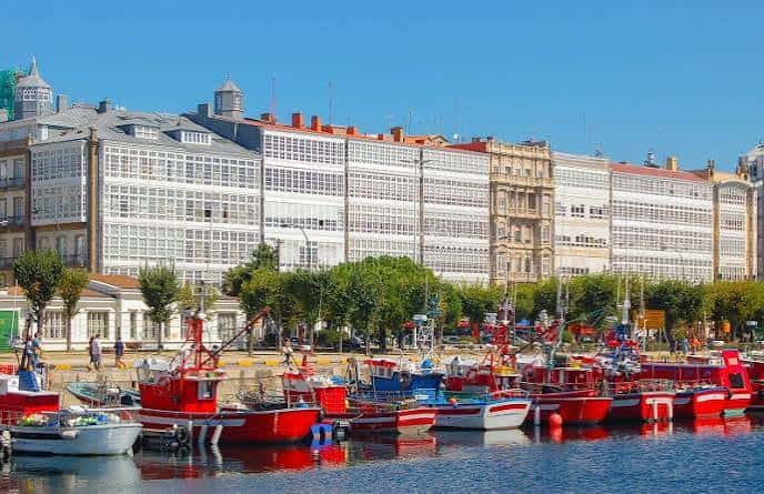 Avenida de Montoto frente al puerto pesquero con embarcaciones rojas y edificios históricos al fondo