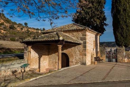 Ermita de San Roque en Henche con fachada de piedra y tejado de tejas bajo cielo azul