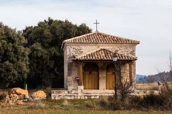 Ermita de San Roque en Mantiel rodeada de árboles y con cruz en la parte superior