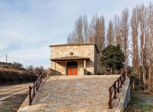 Ermita de San Roque en Budia accesible por puente de piedra con árboles al fondo
