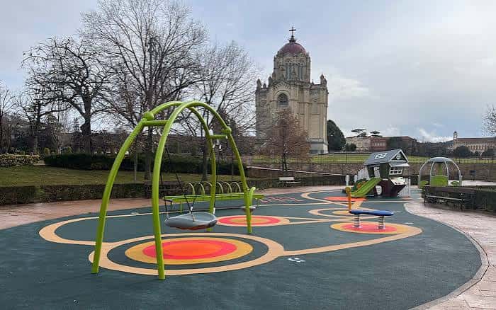 Área de juegos infantiles inclusiva en el Parque de Adoratrices con la Basílica de Guadalupe al fondo