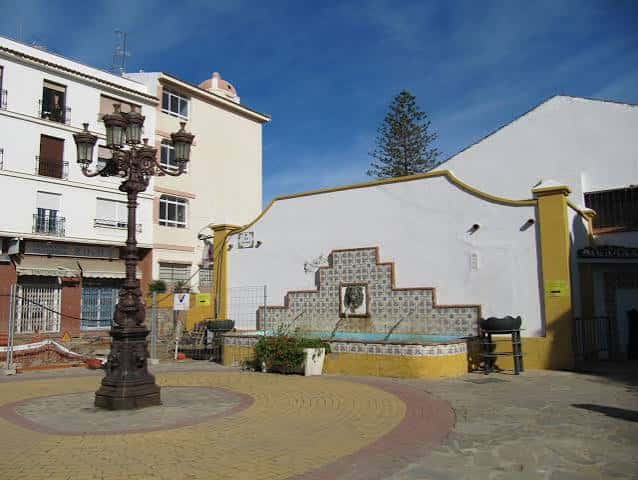 Detalle de la fuente decorativa con azulejos y la estatua en la plaza