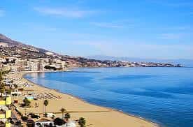 Playa de Carvajal con arena dorada, sombrillas y el mar en calma bajo cielo despejado