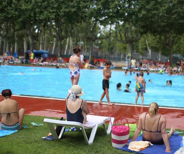 Familias disfrutando de la piscina pública en un día soleado