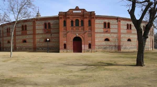 Vista exterior de la Plaza de Toros La Caprichosa en Talavera de la Reina, mostrando su fachada de ladrillo y piedra con arcos y puerta central