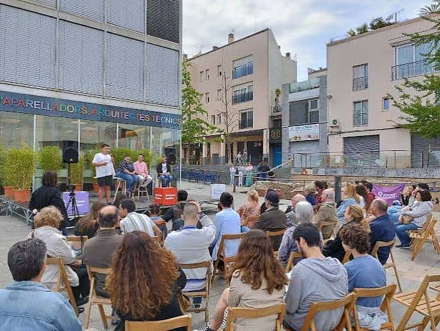 Evento al aire libre en la plaza con público sentado y panelistas en escenario