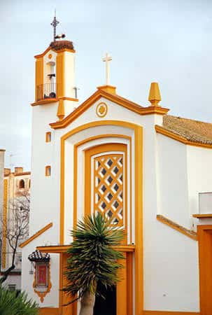 Detalle arquitectónico de la entrada principal de la parroquia, con molduras amarillas y cruz en la parte superior