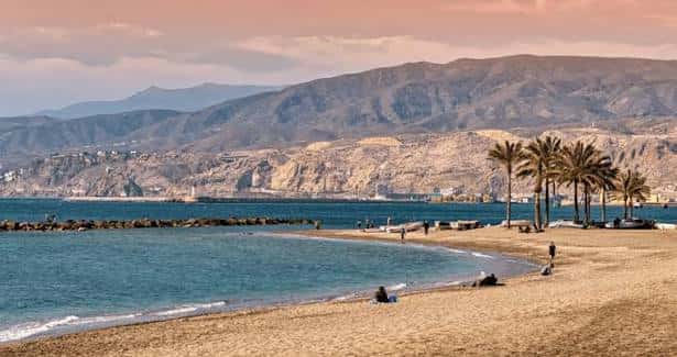Playa del Zapillo con palmeras y montañas al atardecer