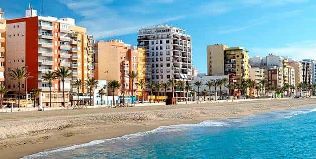 Vista panorámica de la playa con edificios costeros y palmeras