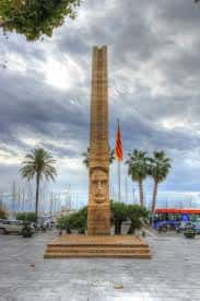 Vista completa del Monumento a Francesc Macià con bandera catalana y palmeras al fondo