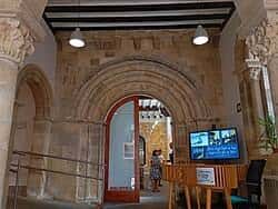 Entrada principal con arcos de piedra, columnas ornamentadas y un mostrador de información con pantalla digital