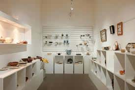 Espacio interior de la galería con estanterías y vitrinas mostrando piezas de cerámica