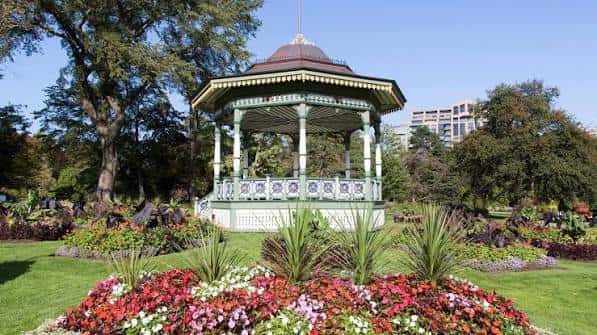 Kiosco de música rodeado de lechos de flores coloridos y césped verde
