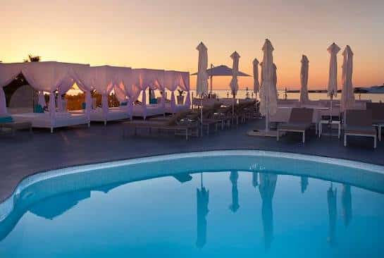 Zona de piscina al atardecer con hamacas y sombrillas, ideal para eventos relajantes