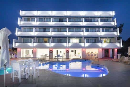 Fachada iluminada del hotel Marina Playa Hotel Apartments por la noche con piscina en primer plano