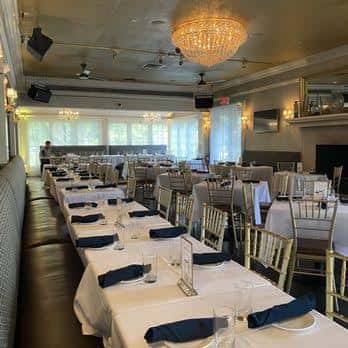 Sala de banquetes interior del Southampton Social Club con mesas dispuestas para evento y candelabro central