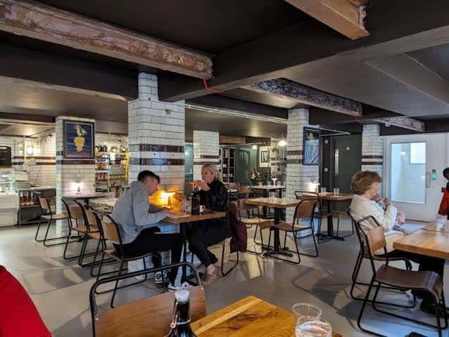 Interior del restaurante con clientes comiendo y decoración de ladrillo blanco