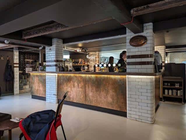Mostrador del bar con grifos de cerveza y columnas de azulejos blancos