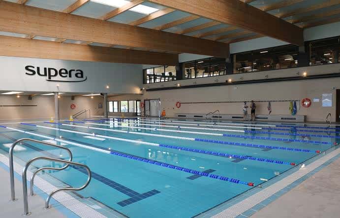 Piscina interior del centro deportivo con carriles y señalización de la marca Supera