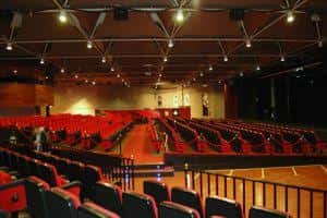 Interior del teatro con iluminación escénica y butacas rojas