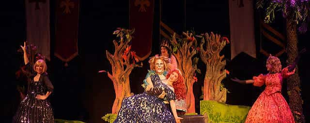 Escena de obra teatral con actores y decorado de bosque