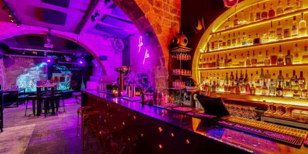 Interior del bar Space Cowboy con iluminación de neón y estantería de botellas