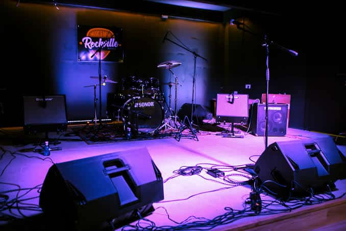 Escenario de la sala Rockville con instrumentos musicales y luces de concierto