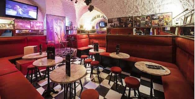 Interior del local con mesas, sillas rojas y decoración temática de música