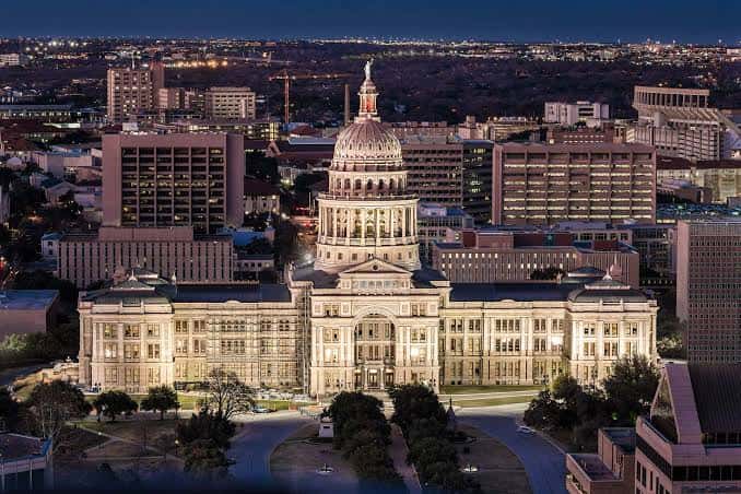 Vista nocturna del Capitolio de Texas con la cúpula iluminada y la ciudad de Austin al fondo