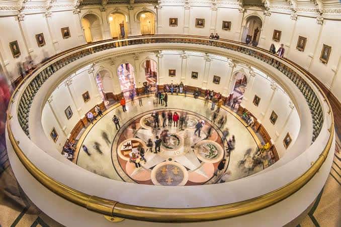 Interior del rotondo del Capitolio de Texas con suelo decorativo y visitantes caminando