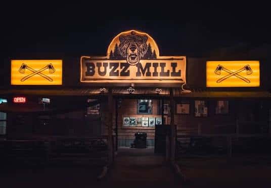 Fachada principal del Buzz Mill con el letrero iluminado y el logo del oso