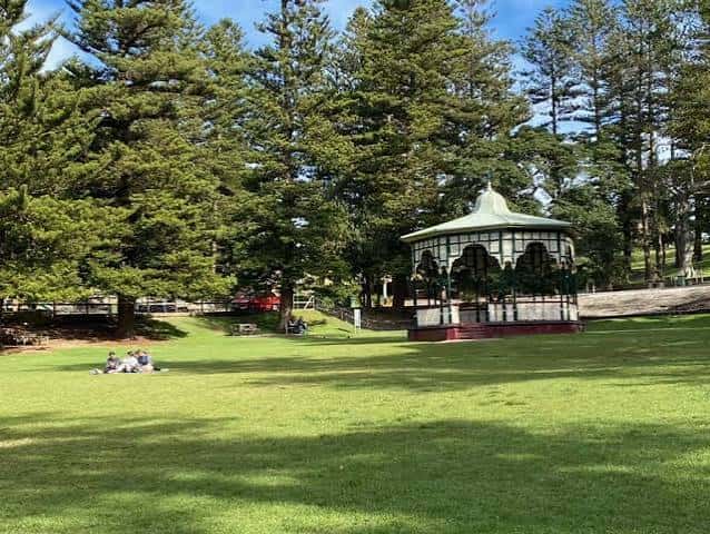 Pabellón de música histórico rodeado de césped y árboles en el parque