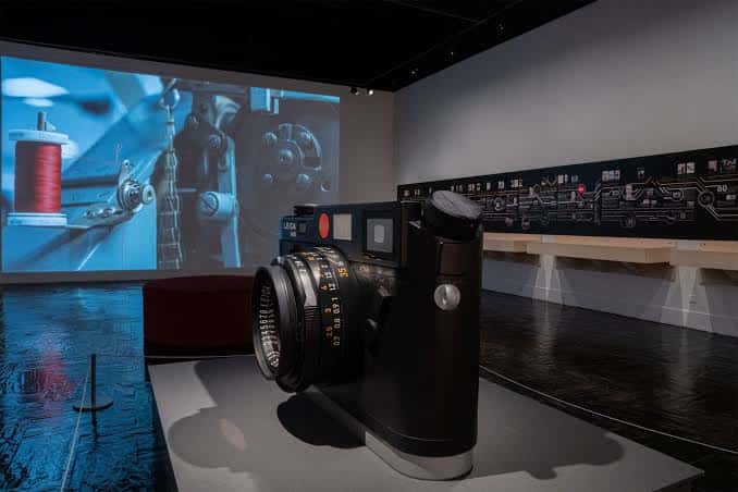 Exhibición de una cámara Leica en un entorno de museo con proyección de fondo