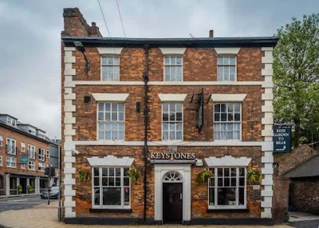 Vista frontal del pub The Keystones, mostrando su arquitectura tradicional y entrada principal con macetas colgantes