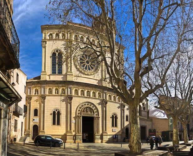 Exterior de la basílica en un día soleado, con árboles y peatones en primer plano