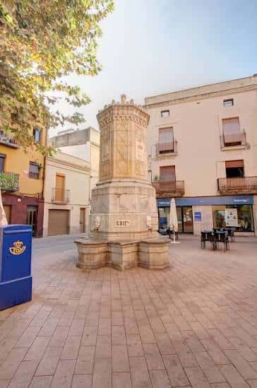 Vista general de la fuente histórica en la Plaça de Miró de Montgròs con mobiliario urbano