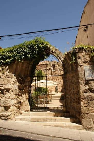 Vista exterior de la Iglesia de San Pantaleón con arco de entrada y vegetación