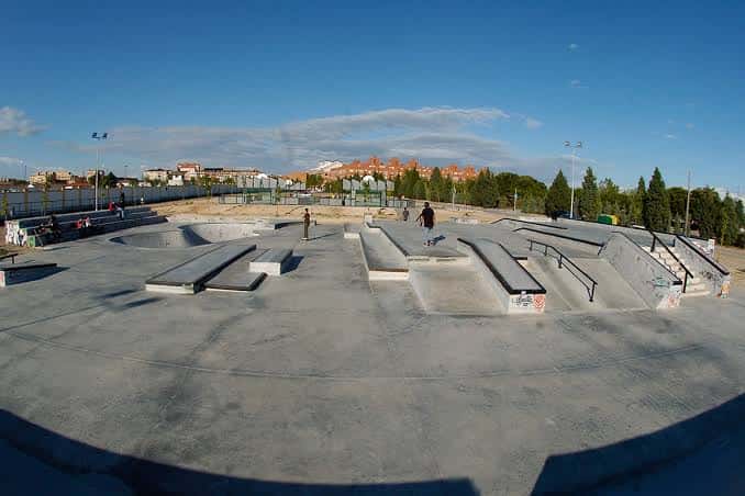Vista panorámica del skatepark con skaters en acción bajo un cielo despejado