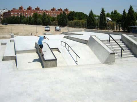Skater realizando un truco en una barra de deslizamiento con edificios al fondo