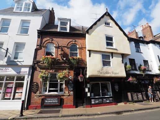 Vista exterior diurna del pub The Golden Slipper en York, mostrando su fachada histórica con detalles arquitectónicos y macetas colgantes