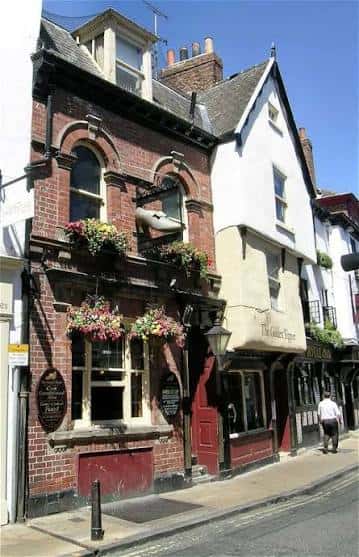 Fachada lateral del pub The Golden Slipper en York, con detalles arquitectónicos y macetas colgantes