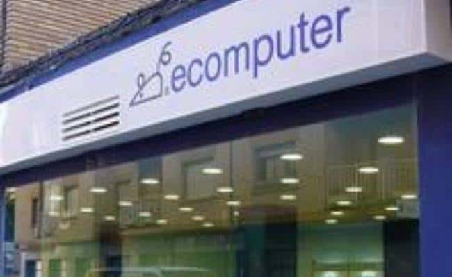 Fachada de tienda Ecomputer con logotipo visible y escaparate interior iluminado
