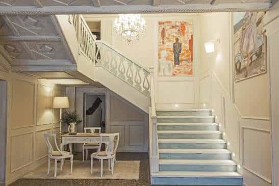Detalle del vestíbulo con mesa de recepción y escalera iluminada