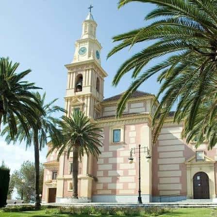 Fachada del Santuario de Nuestra Señora de la Cabeza con palmeras y cielo despejado